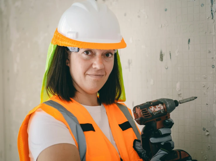 a woman in a hard hat holding a drill, a portrait, pexels contest winner, wearing hi vis clothing, tiling, avatar image, multi - coloured