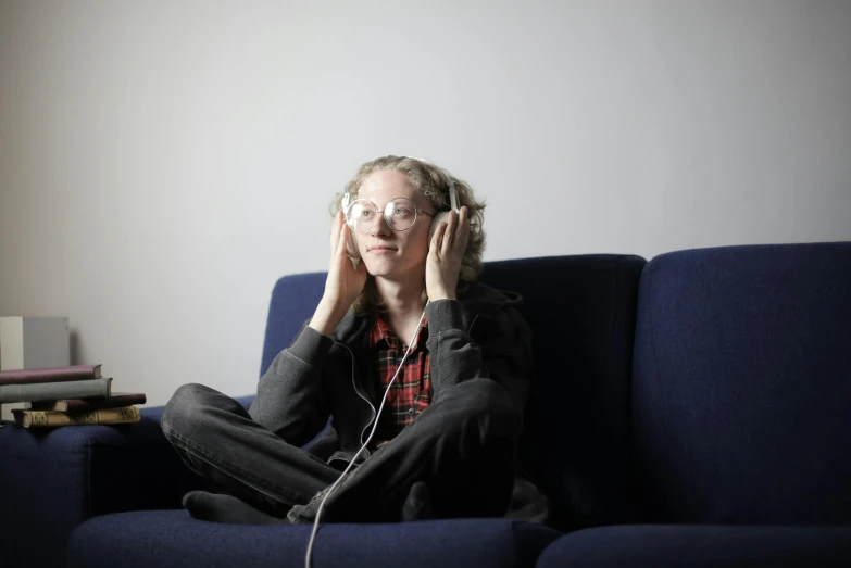 a woman sitting on a couch listening to music, inspired by Louisa Matthíasdóttir, tilda swinton, wearing headset, **cinematic, kiki smith