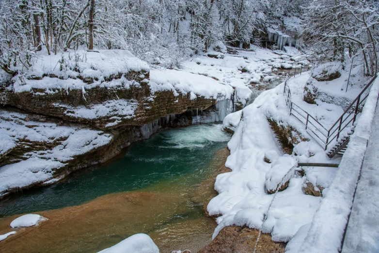 a stream running through a snow covered forest, by Kristin Nelson, pexels contest winner, cave with waterfall, erosion channels river, thumbnail, bentonville arkansas