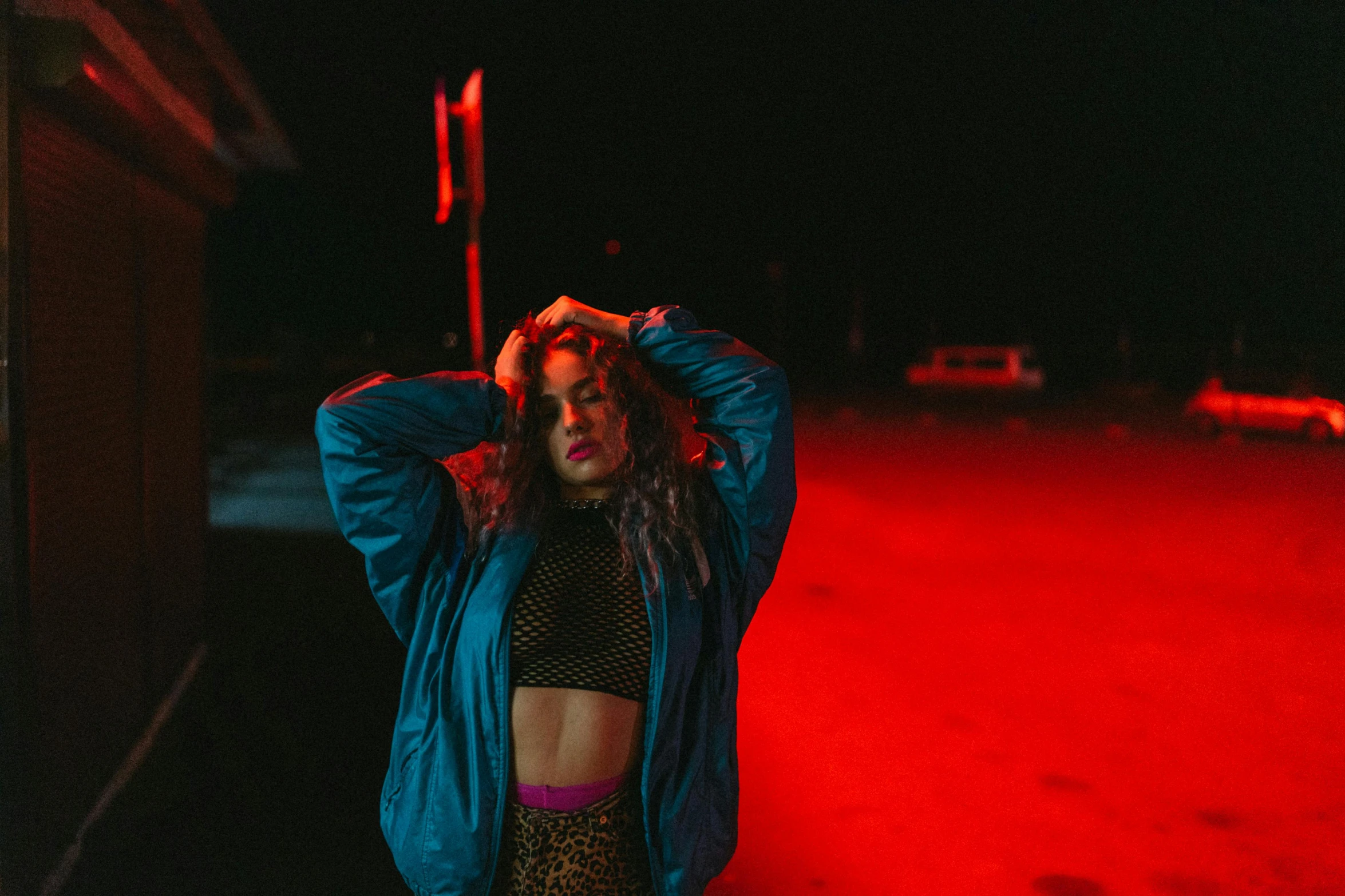 a woman with dreadlocks standing in front of a red light, an album cover, inspired by Elsa Bleda, trending on pexels, graffiti, wearing a neon blue hoodie, charli bowater, physical : tinyest midriff ever, evening lighting