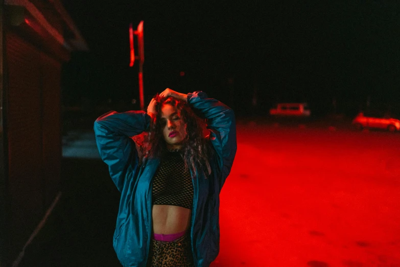 a woman with dreadlocks standing in front of a red light, an album cover, inspired by Elsa Bleda, trending on pexels, graffiti, wearing a neon blue hoodie, charli bowater, physical : tinyest midriff ever, evening lighting