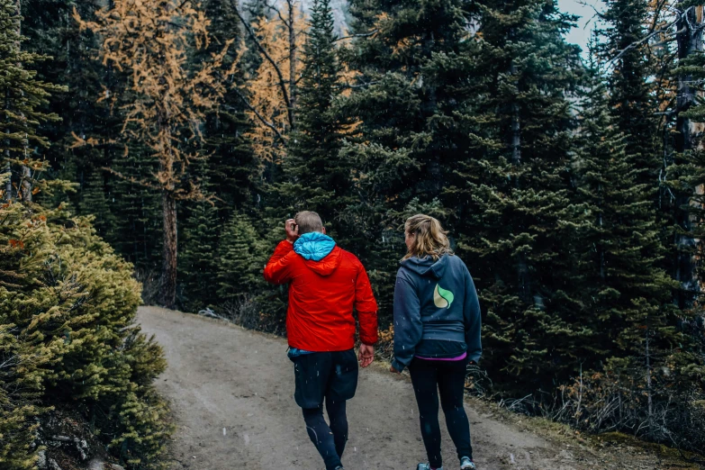 two people walking down a trail in the woods, pexels contest winner, red hoodie, banff national park, 😭🤮 💔, be running up that hill