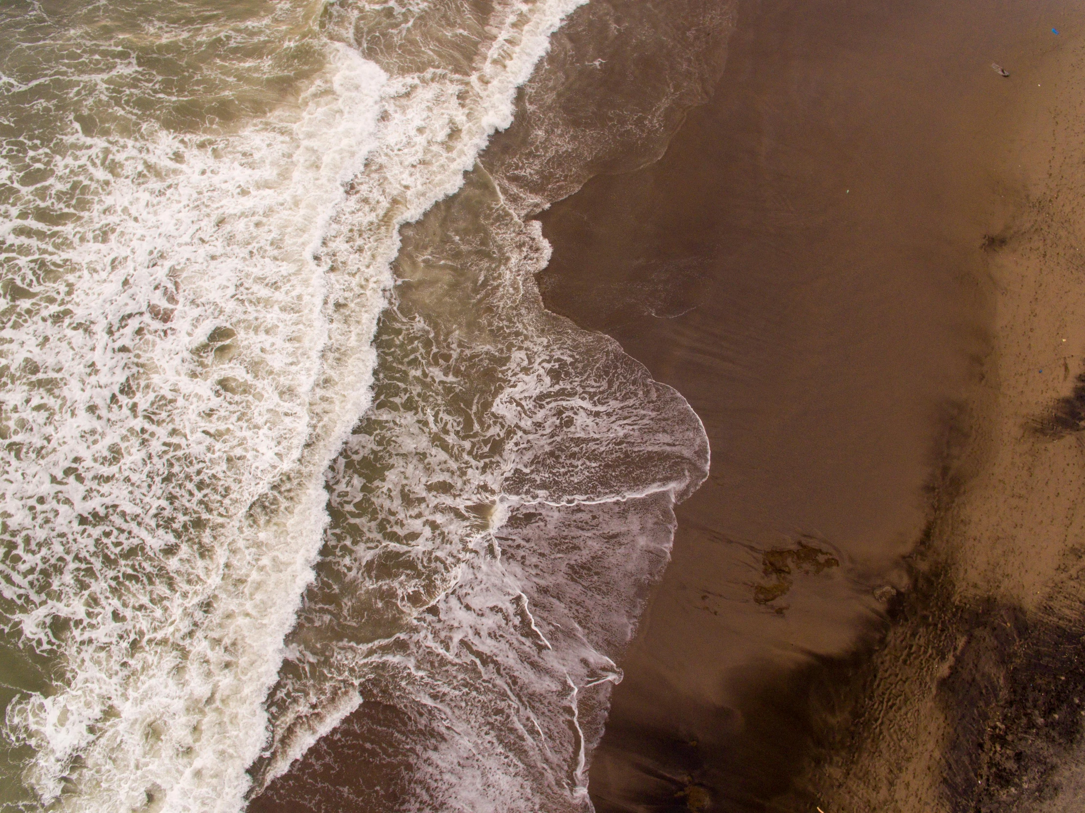 a person riding a surfboard on top of a sandy beach, by Neil Blevins, pexels contest winner, renaissance, view from above on seascape, brown and white color scheme, turbulent water, detailed photo 8 k