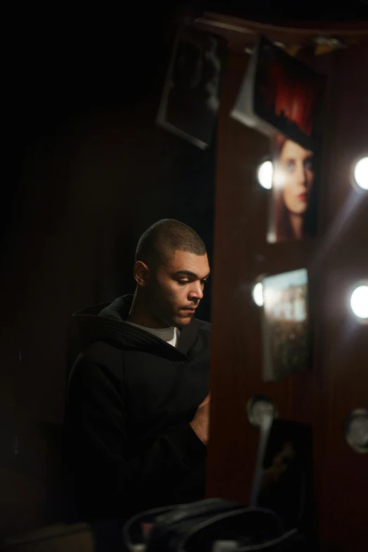 a man standing in front of a mirror in a room, pexels contest winner, photorealism, zayn malik, shot at dark with studio lights, in a black hoodie, theater dressing room