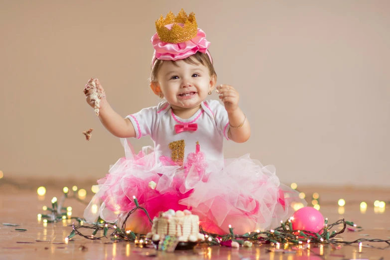 a little girl sitting on the floor with a cake, by Lilia Alvarado, pexels, with crown, pink, boke, happy look