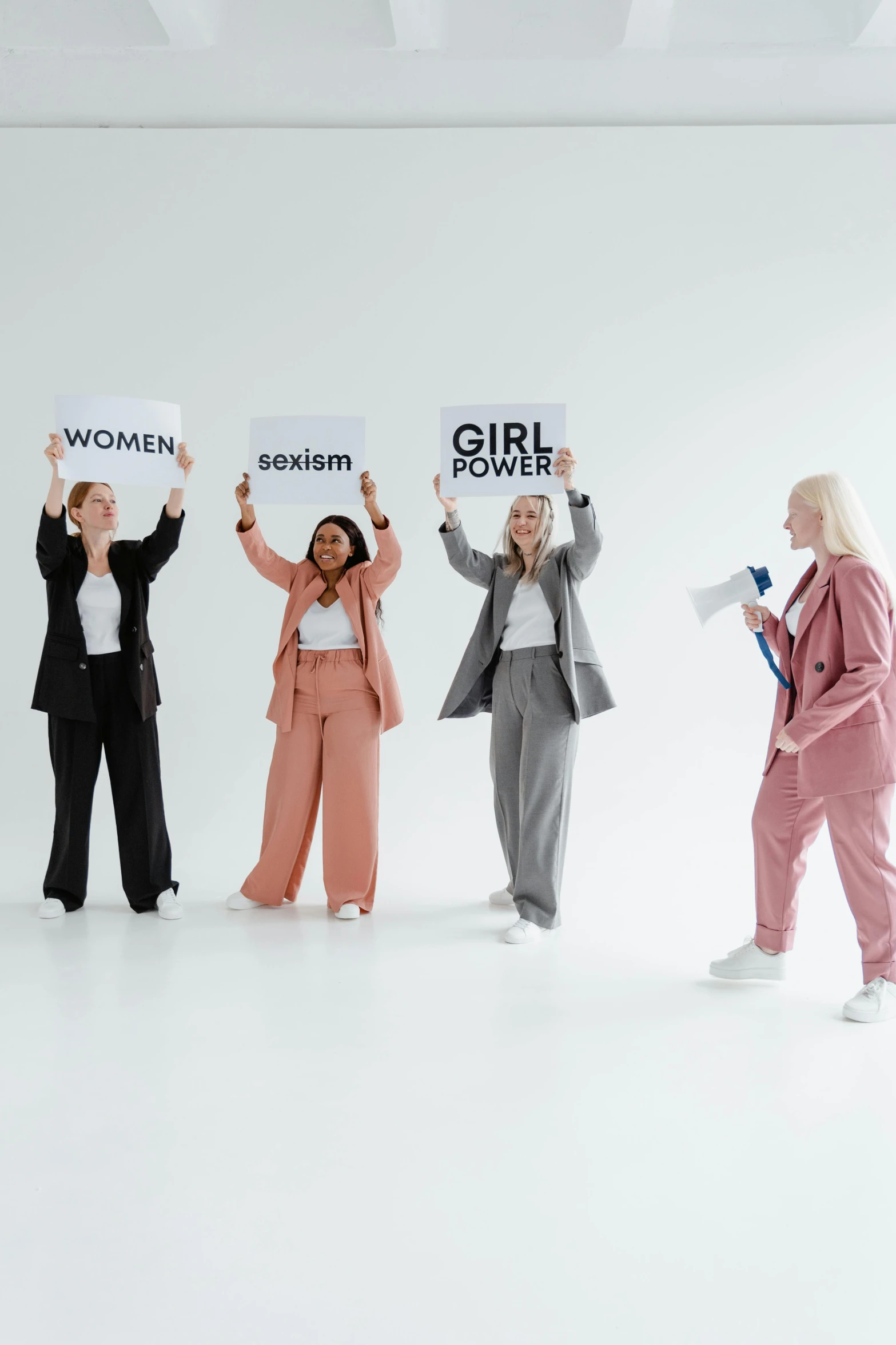 a group of women holding up signs in a room, a cartoon, trending on pexels, full body with costume, studio shoot, girl in a suit, political art