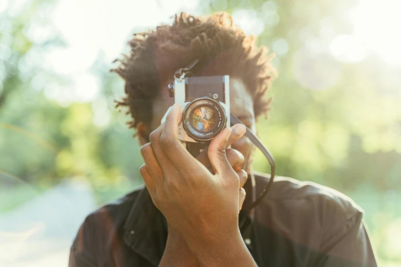 a man taking a picture with a camera, a picture, inspired by Gordon Parks, pexels contest winner, black man with afro hair, discreet lensflare, medium format, getty images proshot