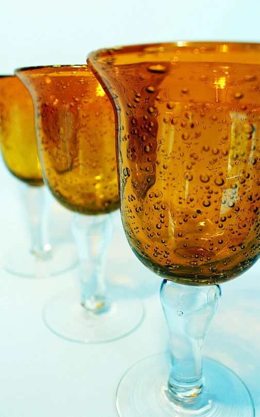 a group of wine glasses sitting on top of a table, jelly - like texture. photograph, amber jewels, promo image, cold beer