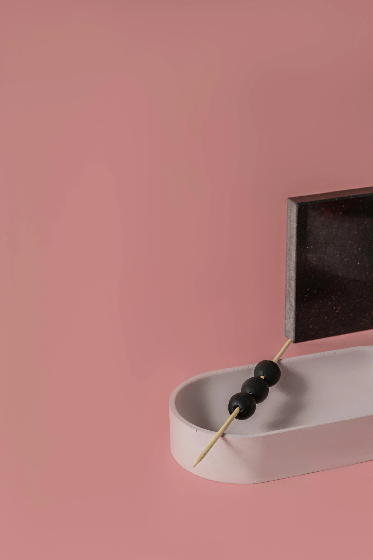 a toothbrush holder with a toothpick sticking out of it, an abstract sculpture, inspired by Lucio Fontana, unsplash, flying black marble balls, minimal pink palette, elaborate oled jewelry, detail shot