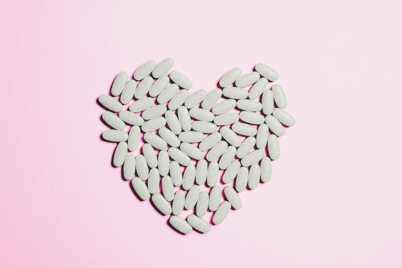 pills in the shape of a heart on a pink background, by Rachel Reckitt, trending on pexels, grey, mullet, beans, hegre