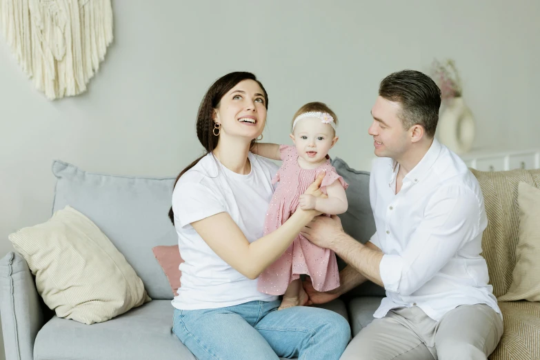 a man and woman sitting on a couch holding a baby, pexels contest winner, hurufiyya, avatar image, cute woman, happy girl, on a white table