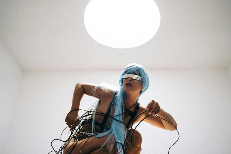 a woman with blue hair in a room, inspired by Shigeru Aoki, unsplash, video art, cables on her body, epic pose, sun behind her, “house music rave with dancers