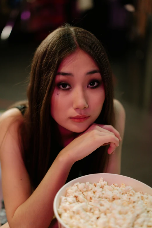 a woman sitting at a table with a bowl of popcorn, an album cover, inspired by Feng Zhu, trending on pexels, girl cute-fine-face, gongbi, ( ( theatrical ) ), early evening