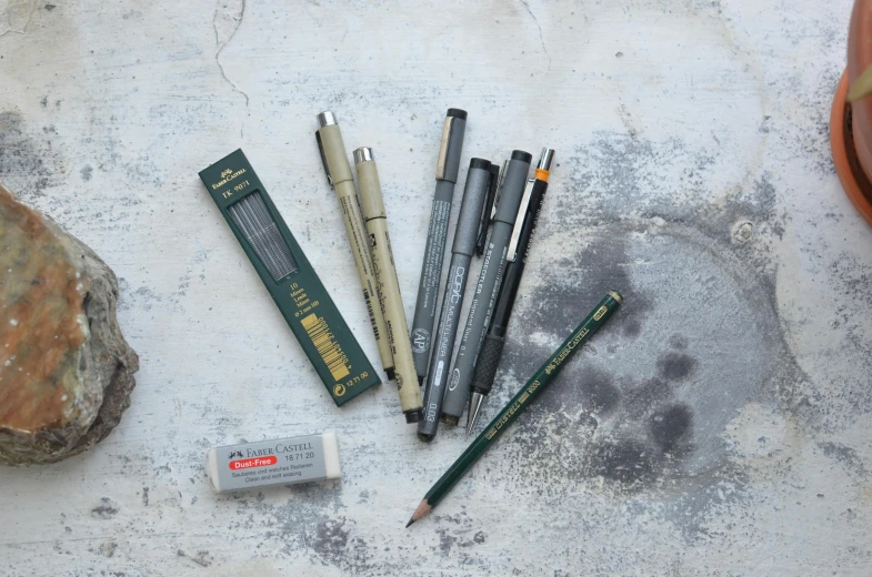 a group of pens sitting on top of a cement floor, a sketch, inspired by Alphonse Legros, japanese collection product, medium: black pencil, full product shot, as well as scratches