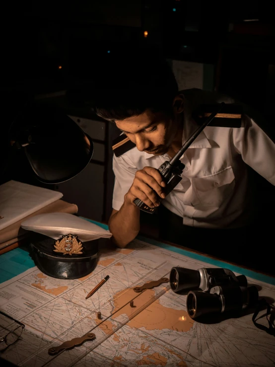 a man sitting at a desk looking through a magnifying glass, pexels contest winner, aircraft carrier scene, low lighting, in uniform, in sci - fi mumbai