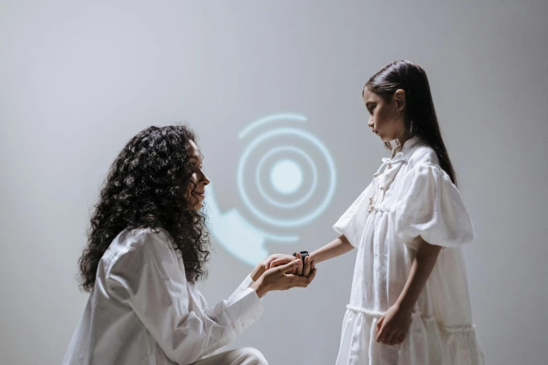 a couple of women standing next to each other, a hologram, inspired by Anna Füssli, pexels contest winner, interactive art, summoning circle, in white room, tactile buttons and lights, reaching out to each other