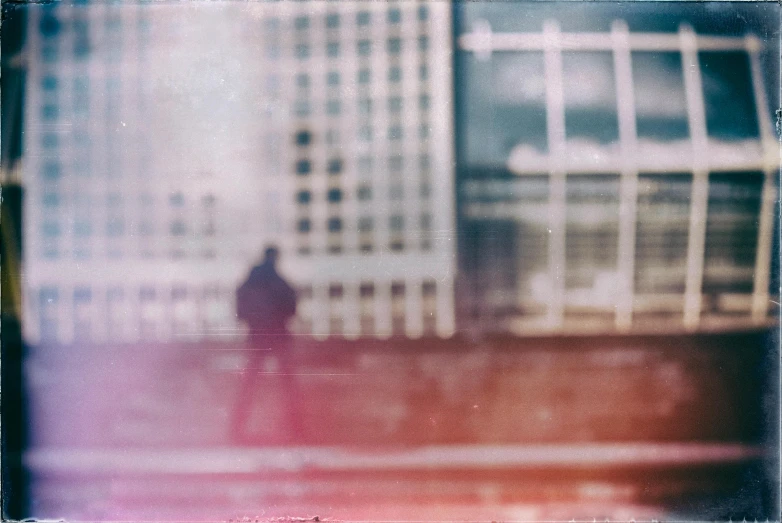 a blurry photo of a person sitting on a bench, a polaroid photo, inspired by Louis Faurer, unsplash, postminimalism, in front of a sci fi cityscape, faded red colors, man walking through city, hasselblad photograph
