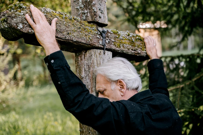 a man standing next to a wooden cross, by Jesper Knudsen, unsplash, renaissance, an 80 year old man, in ecstasy, 15081959 21121991 01012000 4k, david attenborough