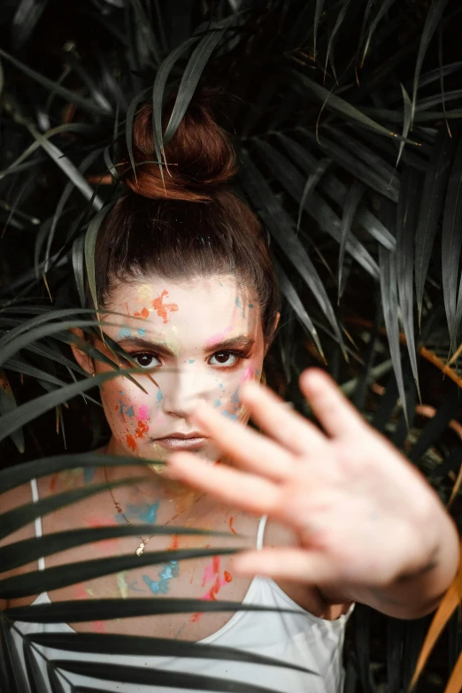 a woman that has some paint on her face, a portrait, inspired by Elsa Bleda, unsplash, palm skin, photo from a promo shoot, teenage girl, hiding