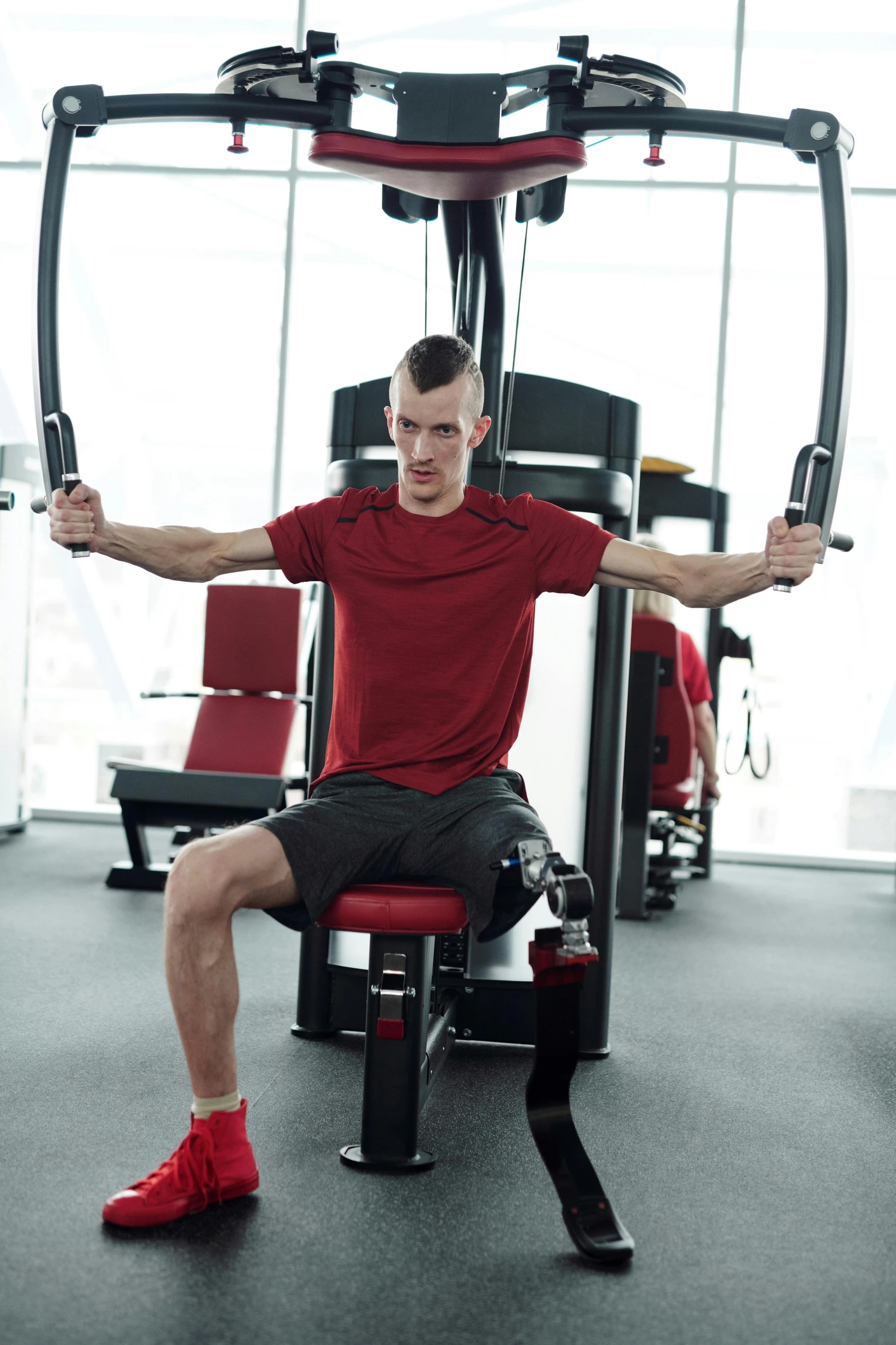 a man sitting on top of a machine in a gym, a portrait, by Adam Marczyński, shutterstock, wearing red tank top, soccer player timo werner, no - text no - logo, square