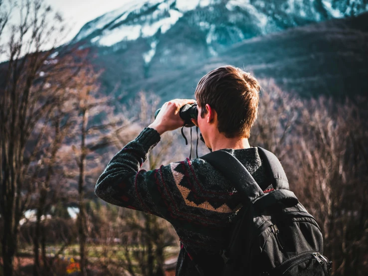 a person taking a picture of a mountain, pexels contest winner, binoculars, college, solo hiking in mountains trees, a photo of a man
