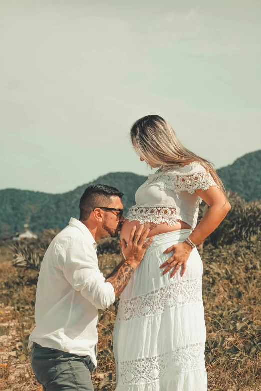 a man kneeling next to a woman in a white dress, pexels contest winner, pregnant belly, instagram post, tattooed, profile image