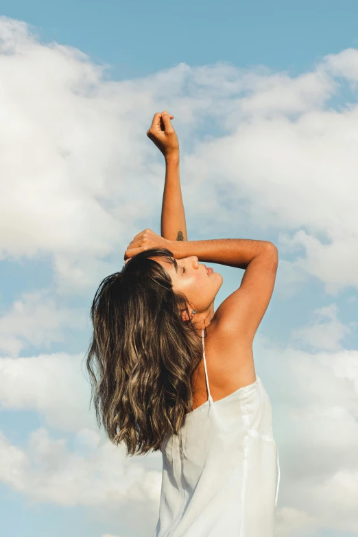 a woman standing on top of a lush green field, trending on unsplash, deep tan skin, reaching for the sky, brunette, profile image