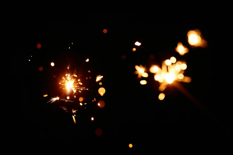 a couple of sparklers in the dark, a picture, shining gold and black and red, glittering stars scattered about, uploaded, taken on iphone 14 pro