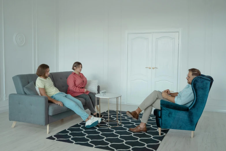 a group of people sitting on a couch in a living room, in a white room, profile image