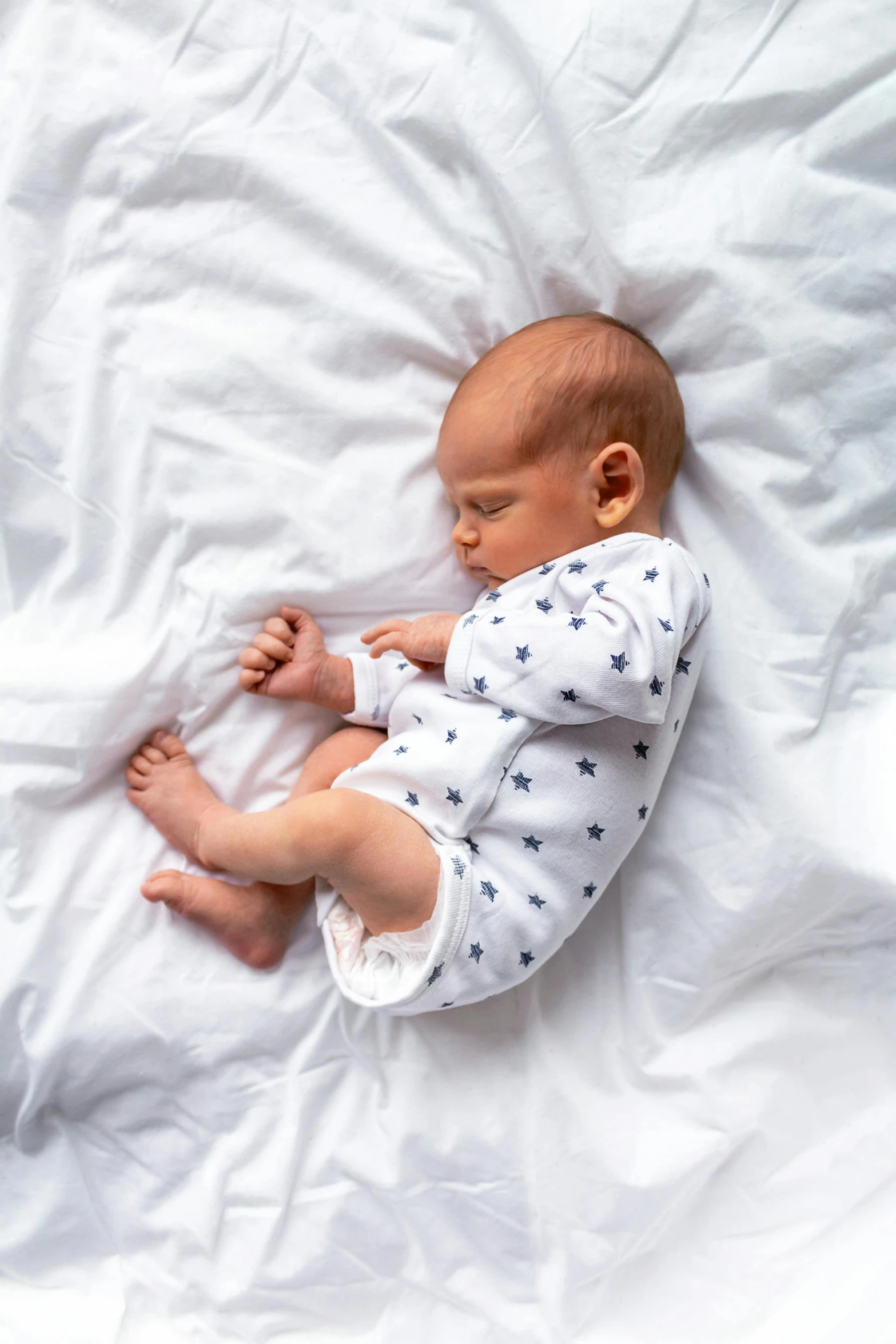 a baby laying on top of a white sheet, inspired by Myles Birket Foster, shutterstock contest winner, very handsome, tiny stars, navy, caspar david