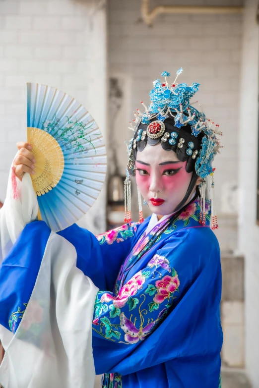 a woman in a blue dress holding a fan, inspired by Lan Ying, pexels contest winner, peking opera, square, ( ( theatrical ) ), white