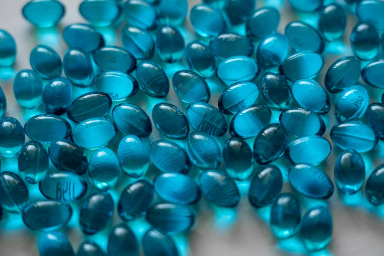 a pile of blue glass beads sitting on top of a table, by Alison Watt, pexels, monochromatic teal, fish, steroid use, amber