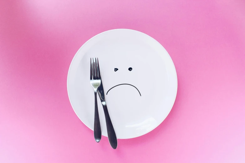 a plate with a sad face drawn on it, a cartoon, by Arabella Rankin, unsplash, postminimalism, pink, food photograph, fork, weightless