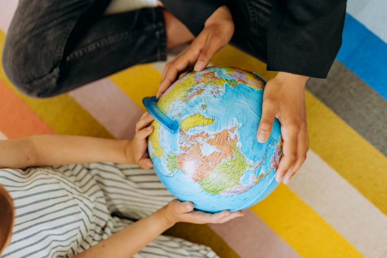 a couple of people that are holding a globe, pexels contest winner, educational supplies, coloured, genevieve gauckler, round-cropped