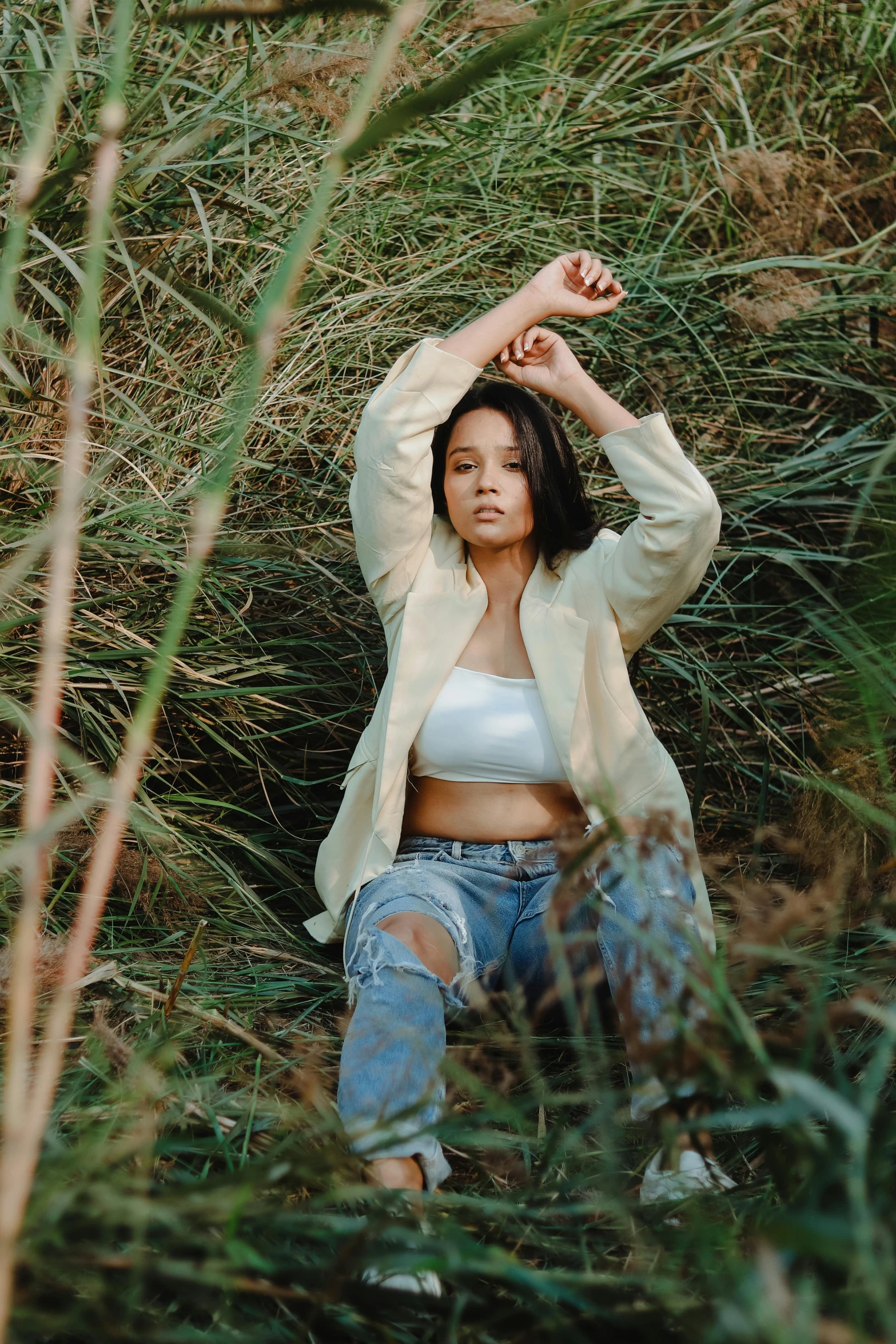 a woman sitting in a field of tall grass, an album cover, unsplash, renaissance, isabela moner, ripped clothing, confident pose, wearing off - white style