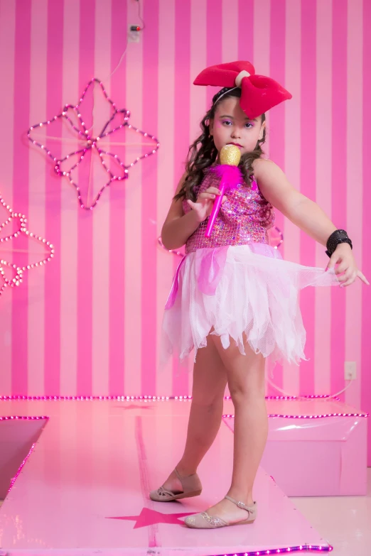 a little girl standing on top of a pink platform, an album cover, by reyna rochin, pexels, singing into microphone, glitter gif, costume, brightly lit pink room