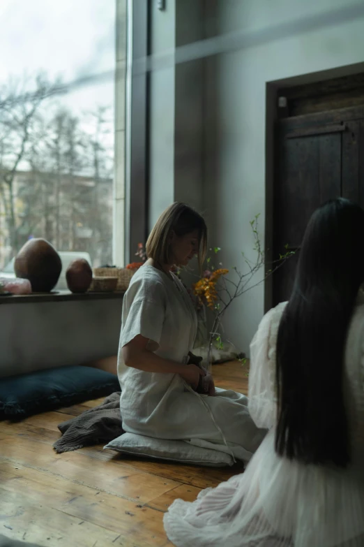 a woman sitting on the floor in front of a window, alessio albi and shin jeongho, ayahuasca ceremony, calmly conversing 8k, ukrainian