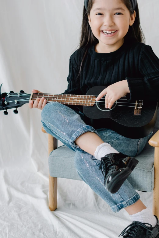 a little girl sitting in a chair with a guitar, trending on unsplash, casual black clothing, wearing kneesocks, a young asian woman, ukulele