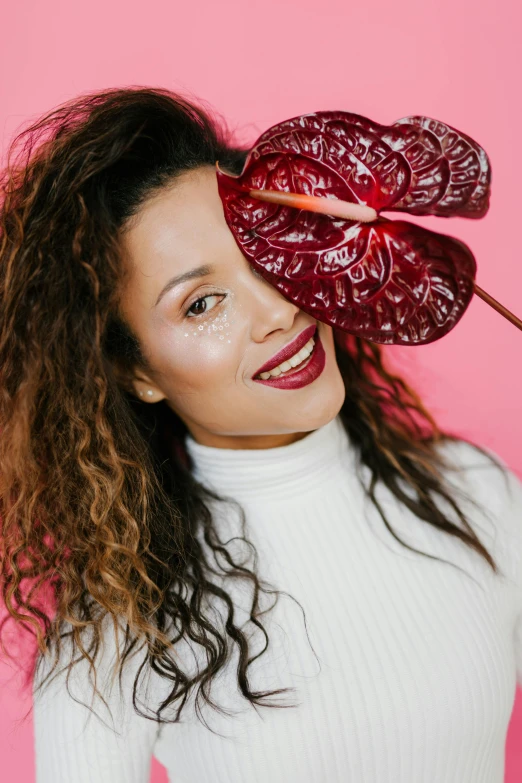 a woman holding a flower in front of her face, an album cover, trending on unsplash, big leaf bra, mixed race, maroon, tongue out