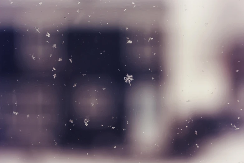 a close up of a window with a building in the background, a microscopic photo, by Emma Andijewska, pexels contest winner, conceptual art, snowflakes falling, white and purple, grainy filter, plain background