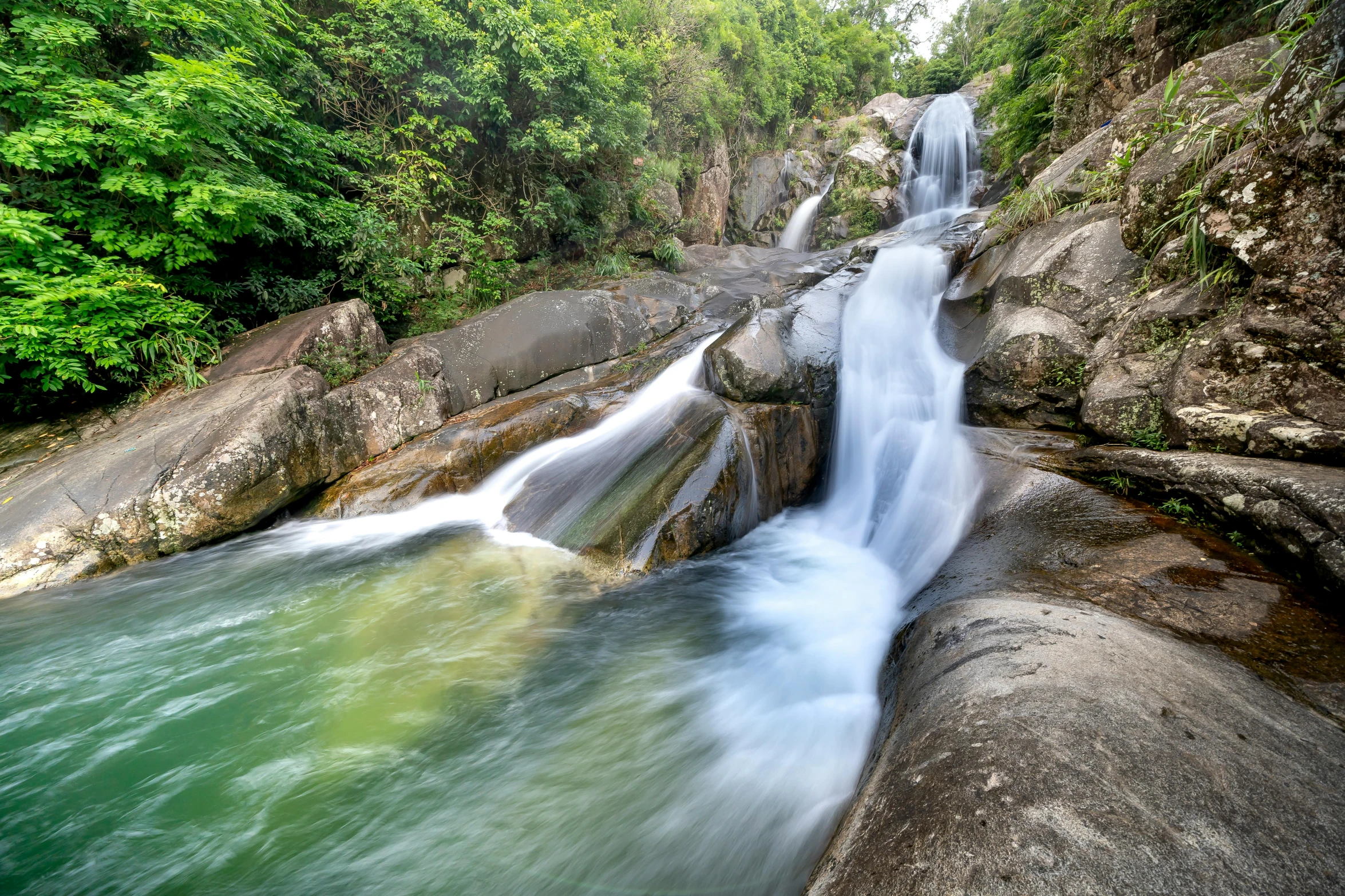 a waterfall flowing through a lush green forest, by Reuben Tam, pexels contest winner, flowing clear water creek bed, malaysia jungle, thumbnail, rock pools