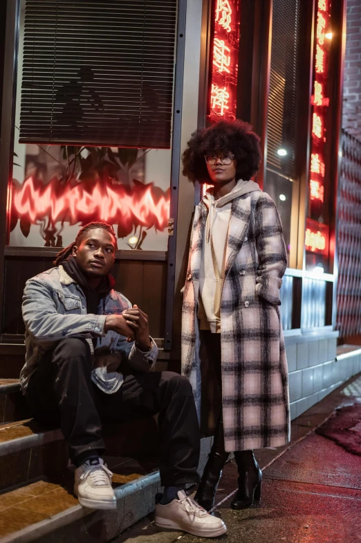 a man and a woman sitting on the steps of a building, a portrait, trending on pexels, black arts movement, model wears a puffer jacket, in front of ramen shop, [ theatrical ], high fashion