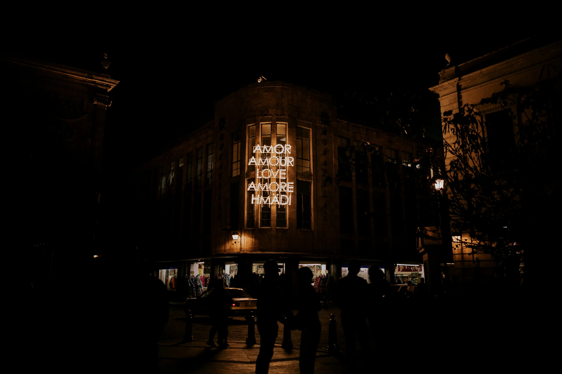 a group of people standing in front of a building at night, by Emma Andijewska, sephora, hidden message, decoration, fall season