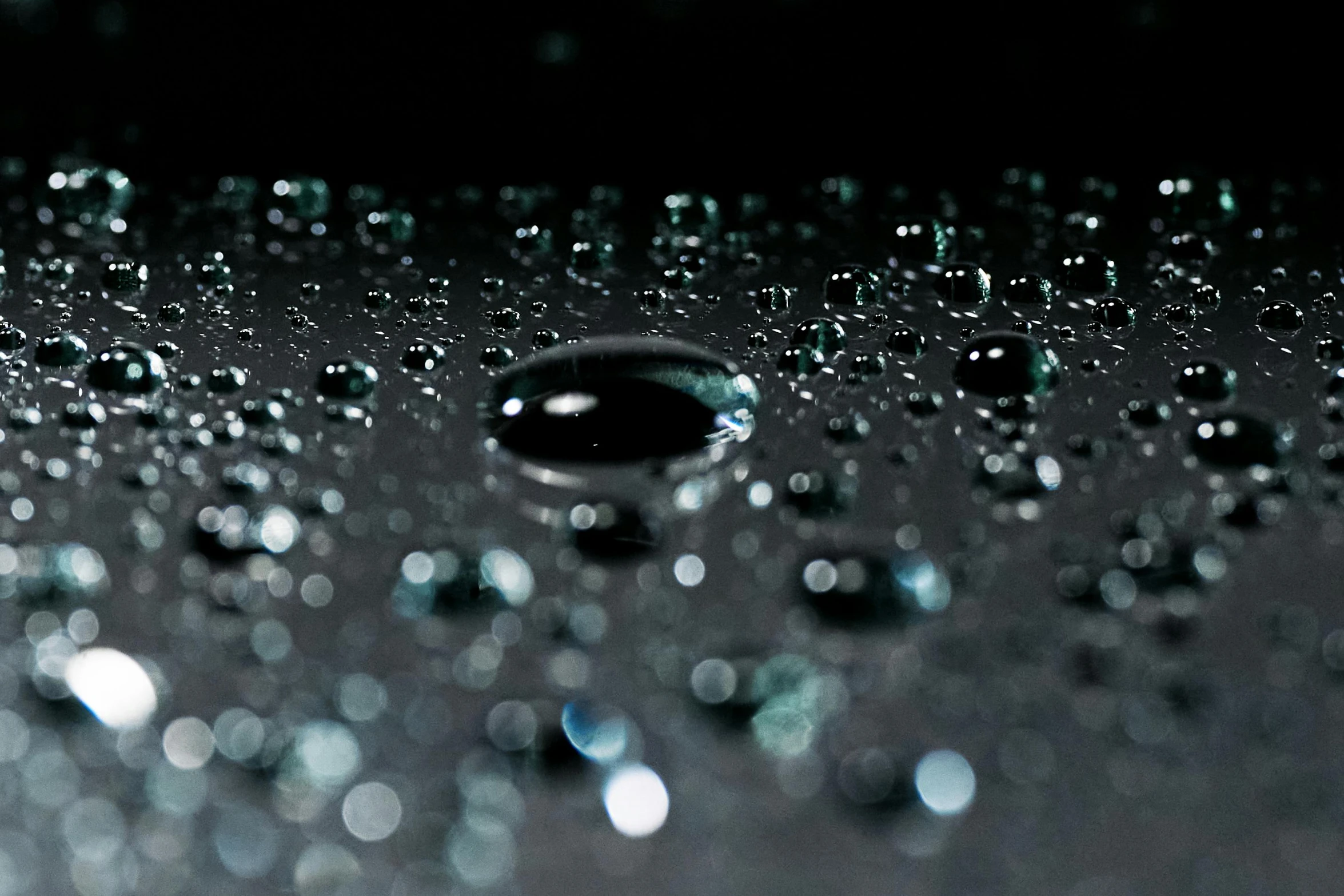 a close up of water droplets on a surface, inspired by Jan Rustem, unsplash, with a black background, 2 0 % pearlescent detailing, sleek waterproof design, wetcore