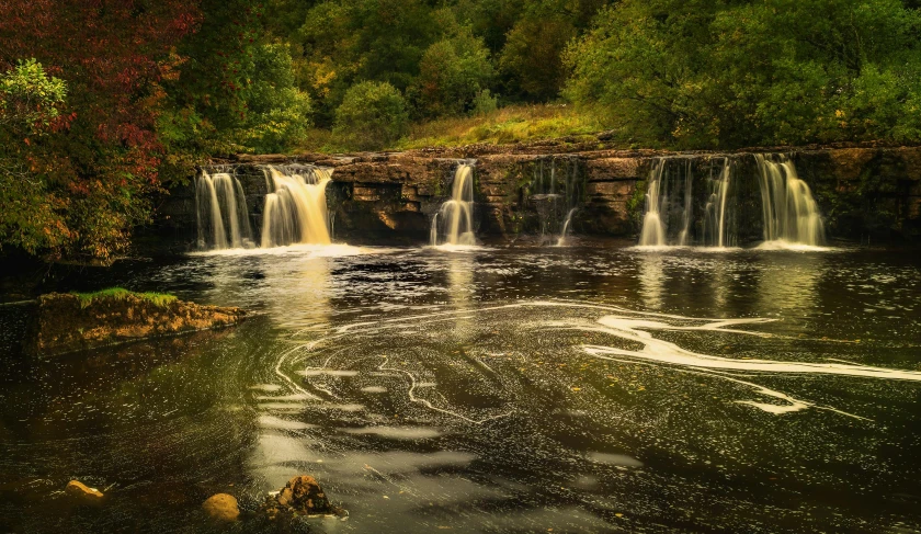 a large waterfall in the middle of a forest, by Andrew Allan, reflections on the river, sandfalls, multiple waterfalls, landscape photo