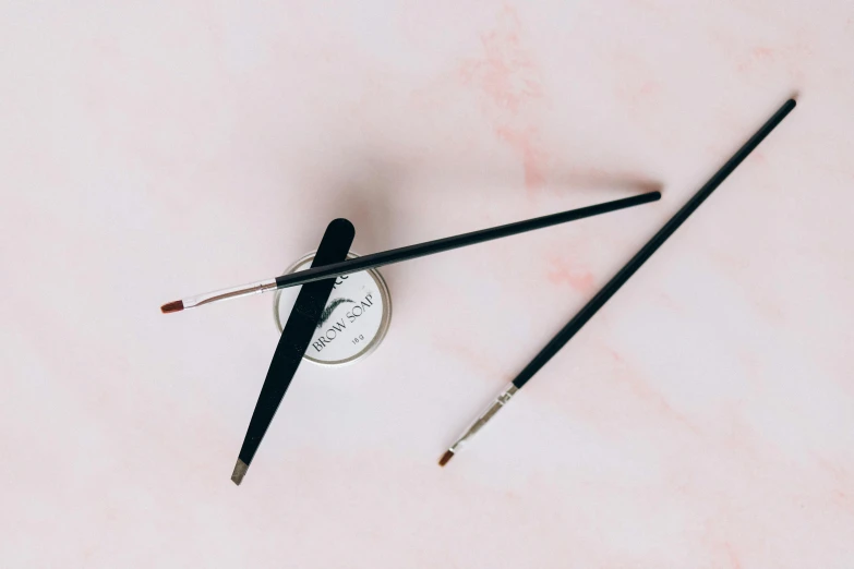 a couple of brushes sitting on top of a table, winged eyeliner, wolfy nail, fine line detail, holding a paintbrush