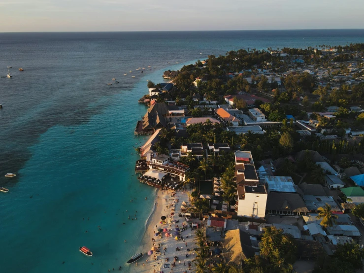 a large body of water next to a beach, pexels contest winner, jamaican vibe, cliffside town, drone footage, evening sun