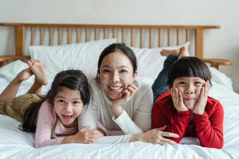 a woman and three children laying on a bed, pexels contest winner, asian origin, avatar image, thumbnail, super high resolution