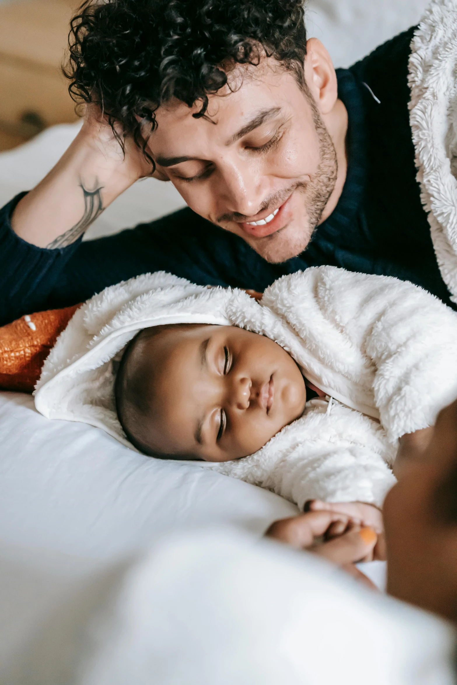 a man laying on top of a bed next to a baby, pexels contest winner, renaissance, mixed race, holding an epée, profile image, lightly dressed