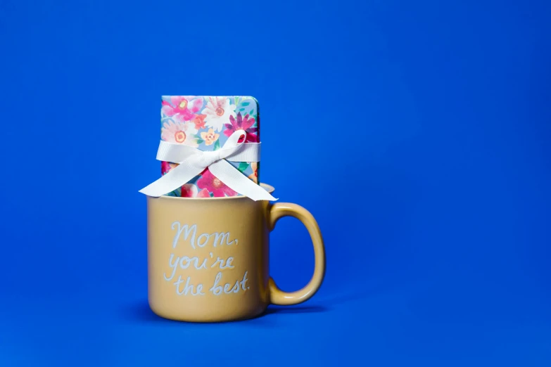 a coffee mug with a gift in it on a blue background, pexels contest winner, dau-al-set, your mom, foil, studio shot, thumbnail